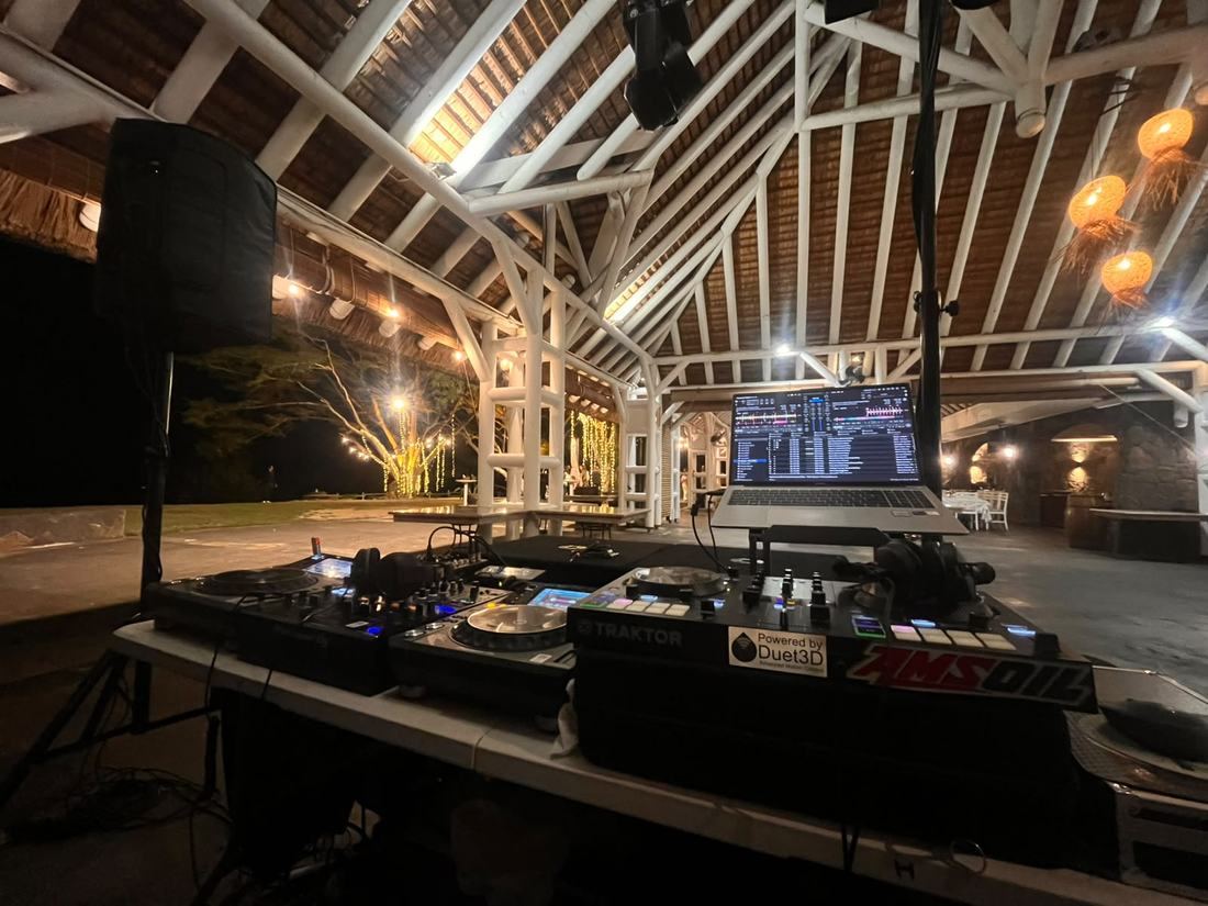 DJ booth under a thatched pavilion roof at dusk